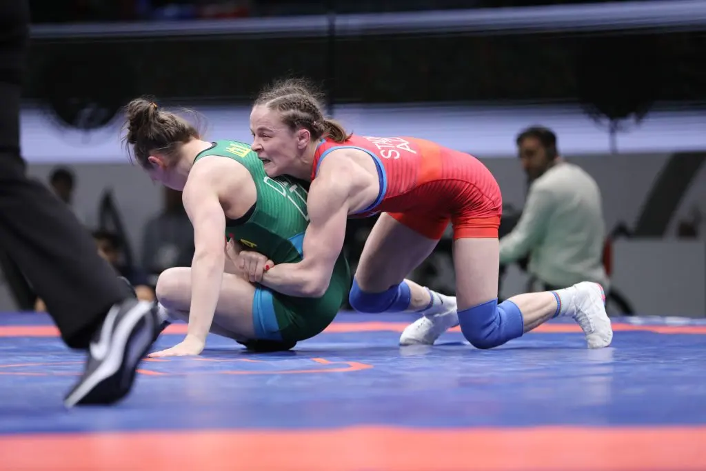 Two freestyle wrestlers scramble for control on a blue mat.