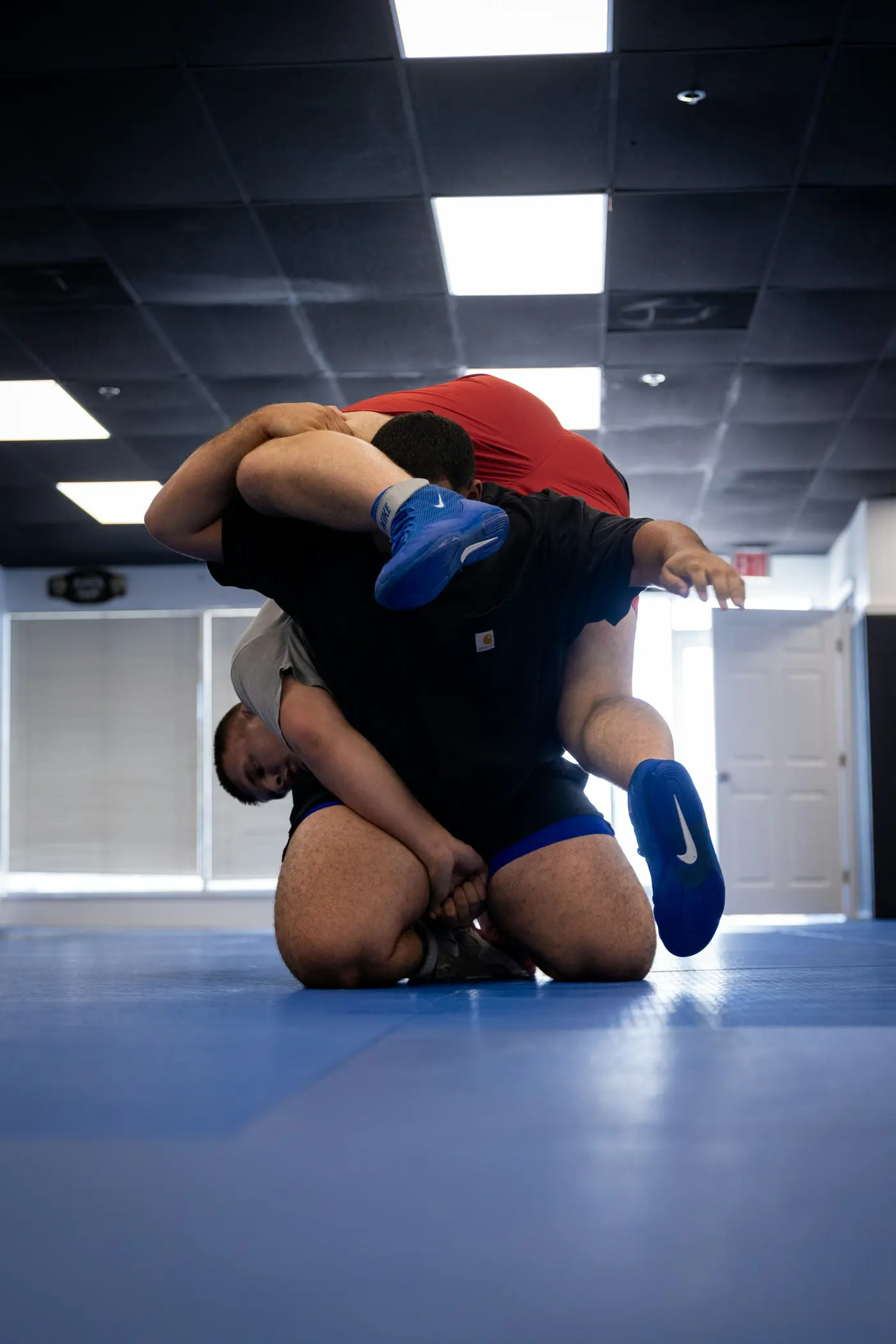 A wrestler drills a throw with a partner in a quiet training room.